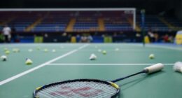 Empty Badminton Court With Scattered Shuttlecocks And Racket.