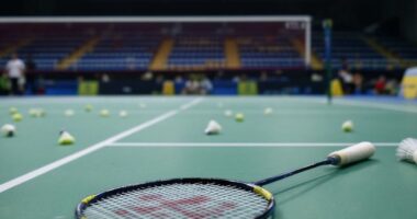 Empty Badminton Court With Scattered Shuttlecocks And Racket.