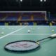 Empty Badminton Court With Scattered Shuttlecocks And Racket.